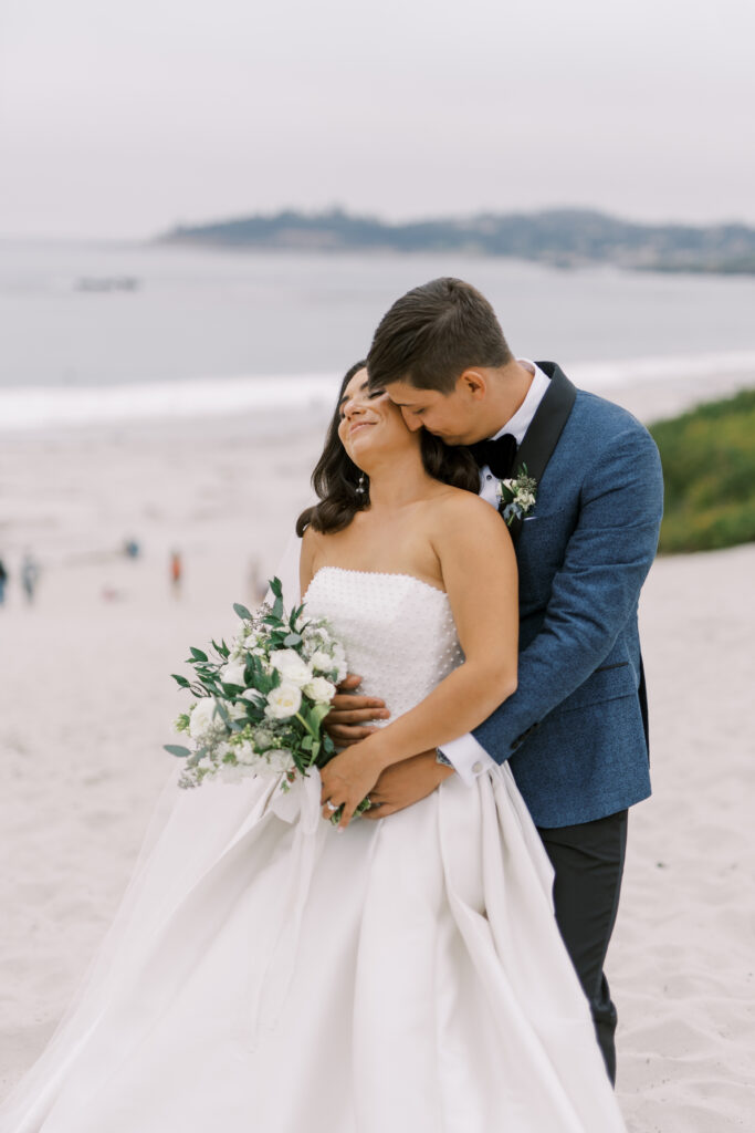 groom holding the bride at the beach