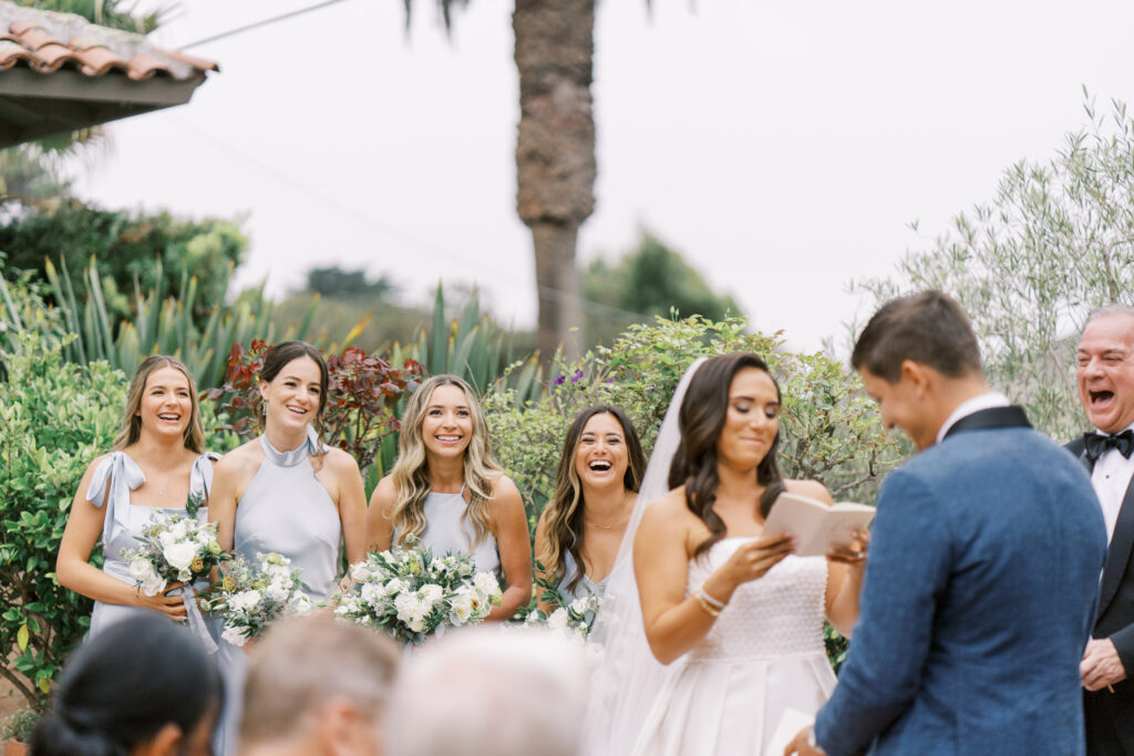 bride reading her vows while bridesmaids are laughing in the background