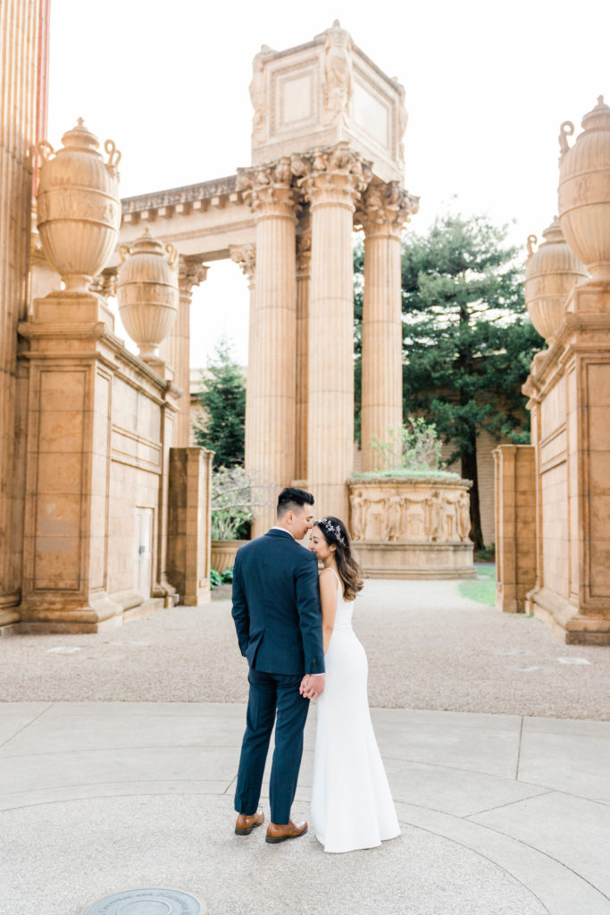 couple smiles into each other's shoulders at palace of fine arts