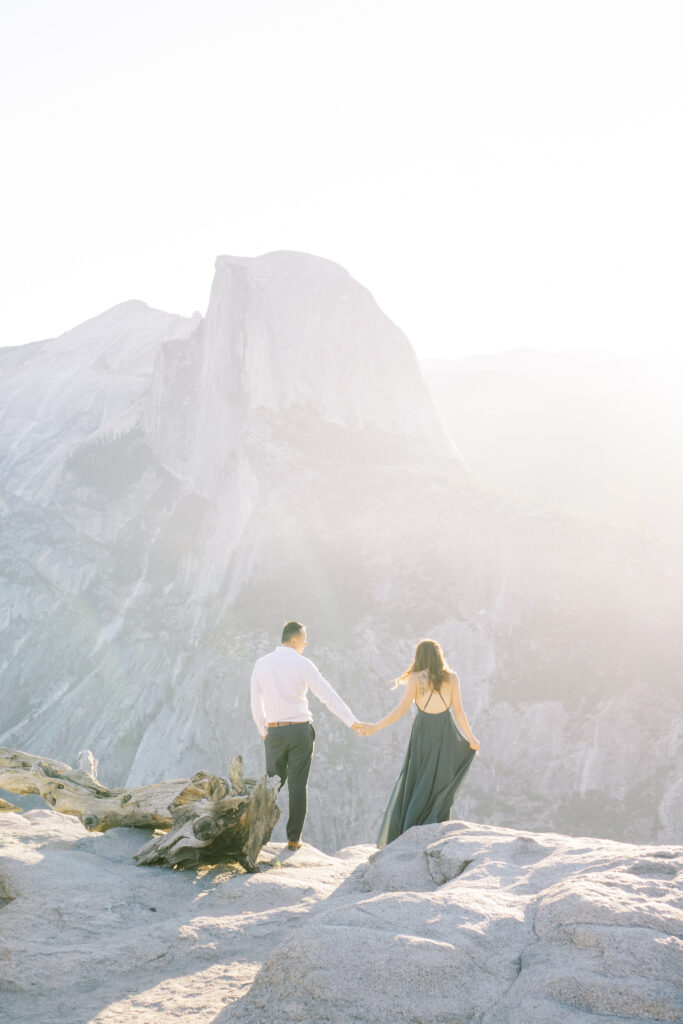 Newly engaged couple holding hands on a mountain cliff