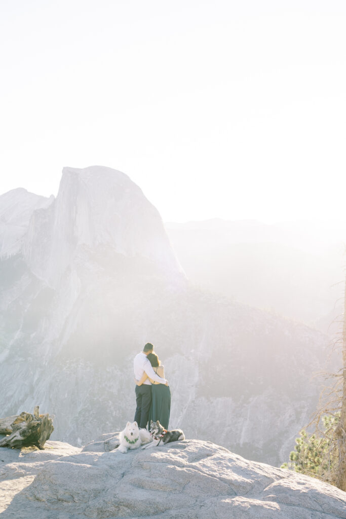 newly engaged photo standing on the cliffside with yosemite on the background