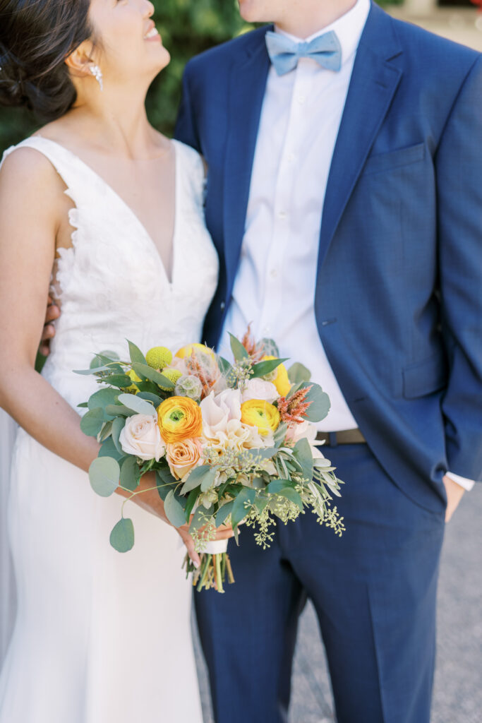 Bride and groom smiling with close-up of wedding bouquet
