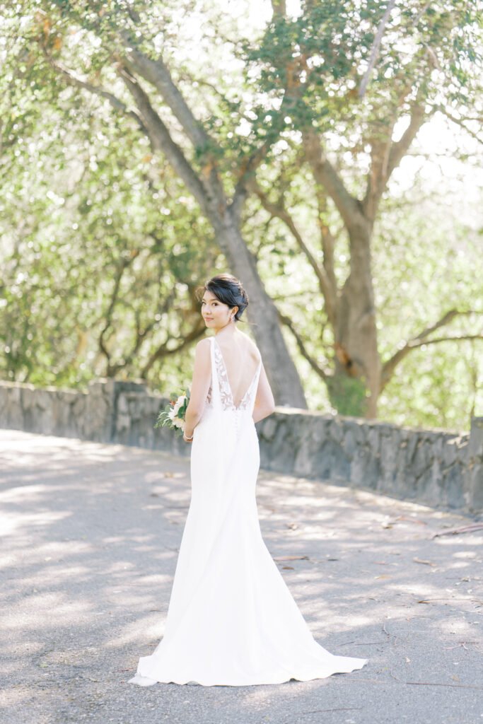 Bride in wedding dress surrounded by lush trees