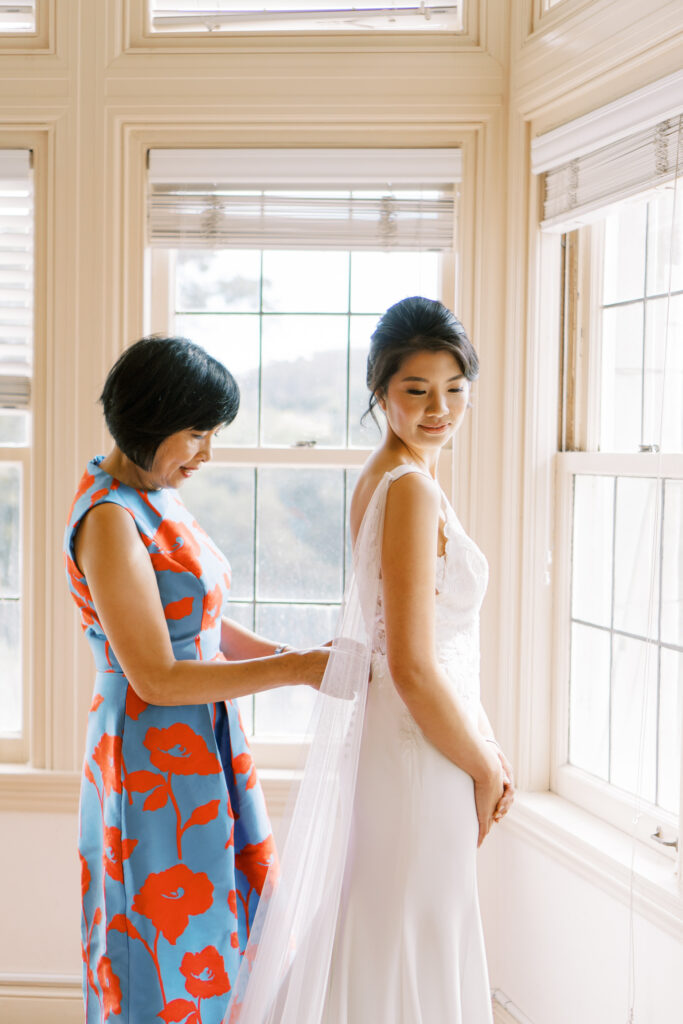 Mother helping daughter with wedding dress