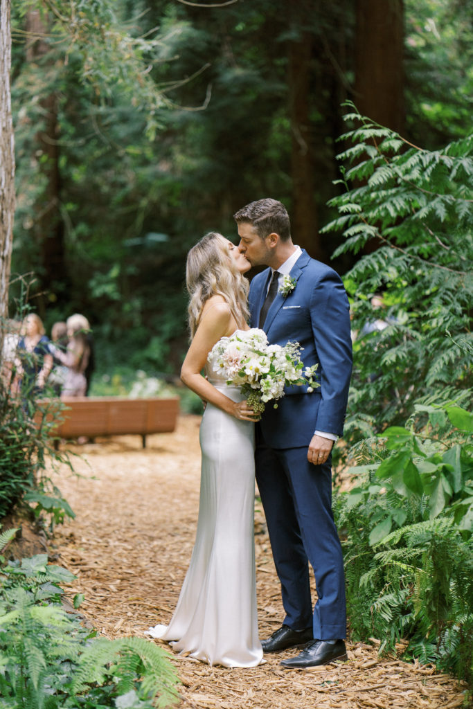 bride and groom kissing among the trees