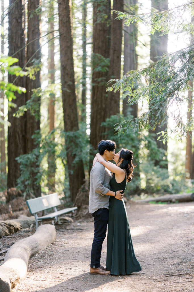 bride and groom kissing in front of trees