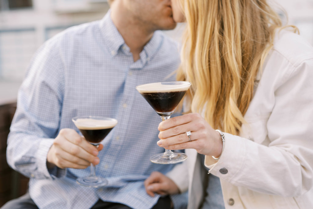 couple kissing while holding drinks