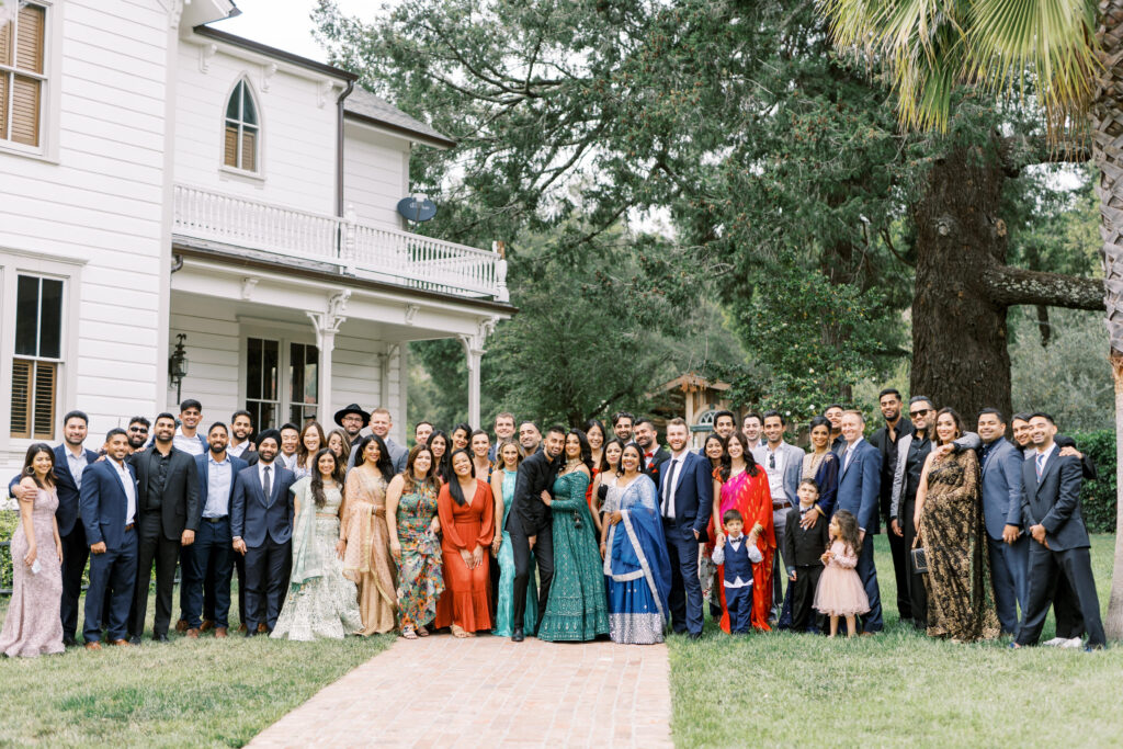Bride and groom with their family and friends smiling together for a group picture