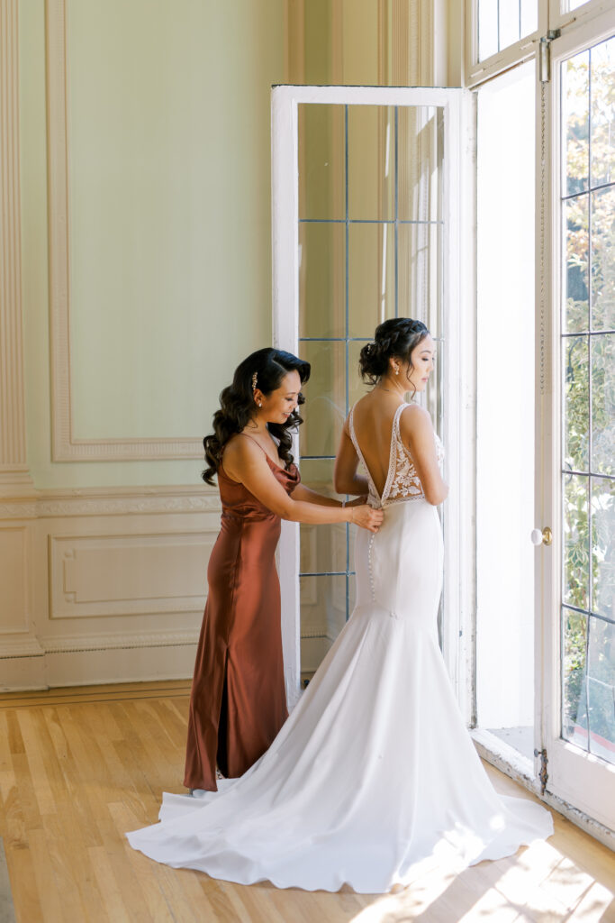 maid of honor helping bride with her gown