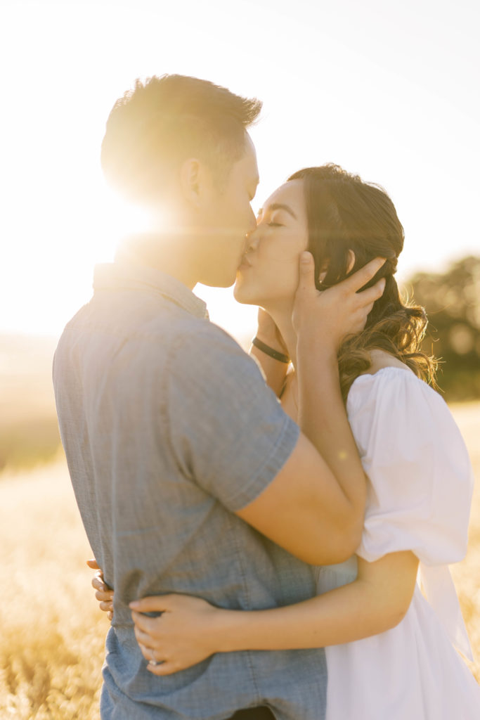 Engaged couple kissing under the golden hour
