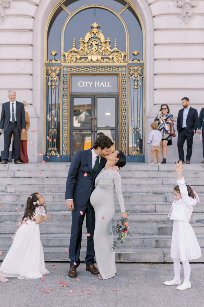 bride and groom kiss at city hall sign
