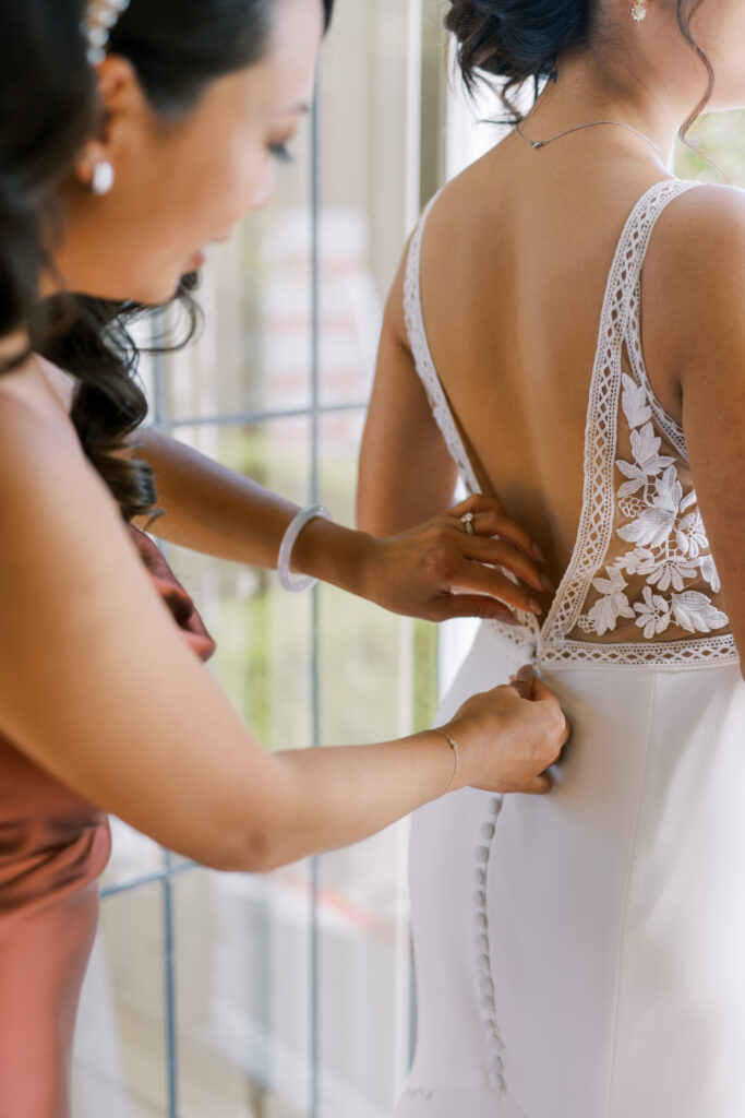 close up of bridal dress getting buttoned