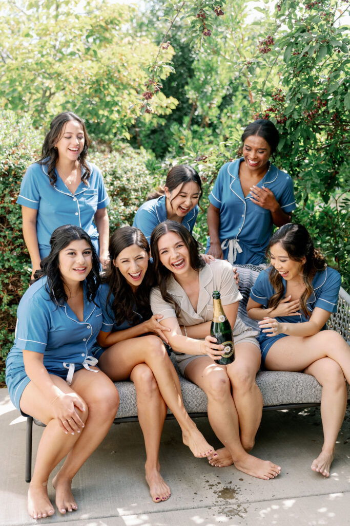 bridal party laughing while bride is holding a champagne bottle