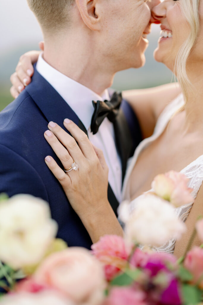 closeup photo of the bride's wedding ring with the couple at the background