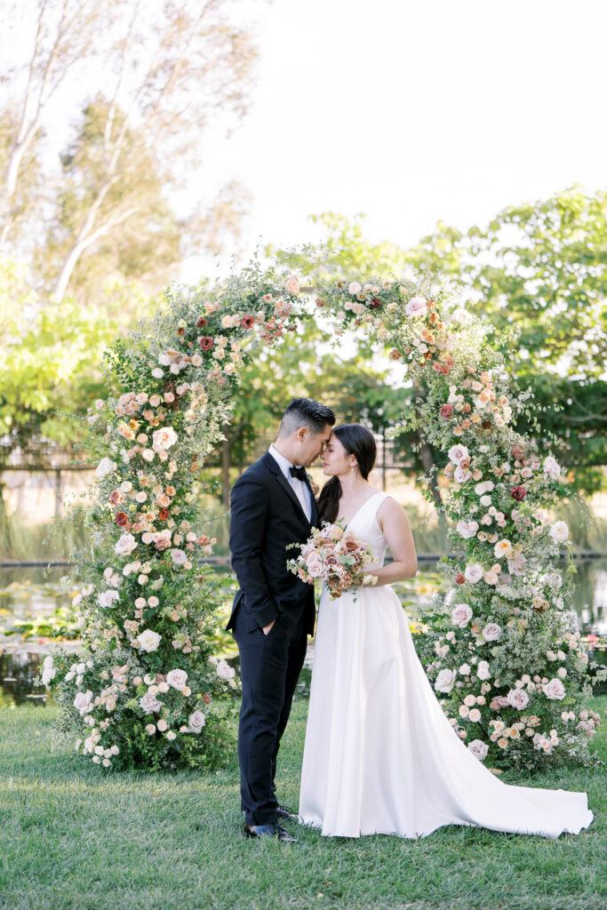 bride and groom posing for a picture at the wedding ceremony arch