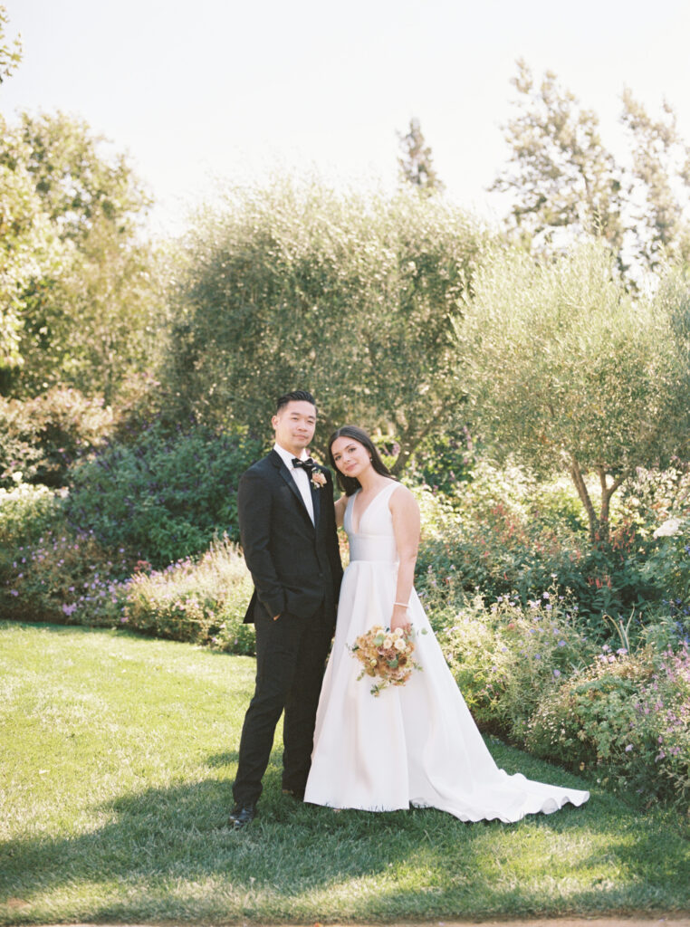 bride and groom posing for a picture in a garden