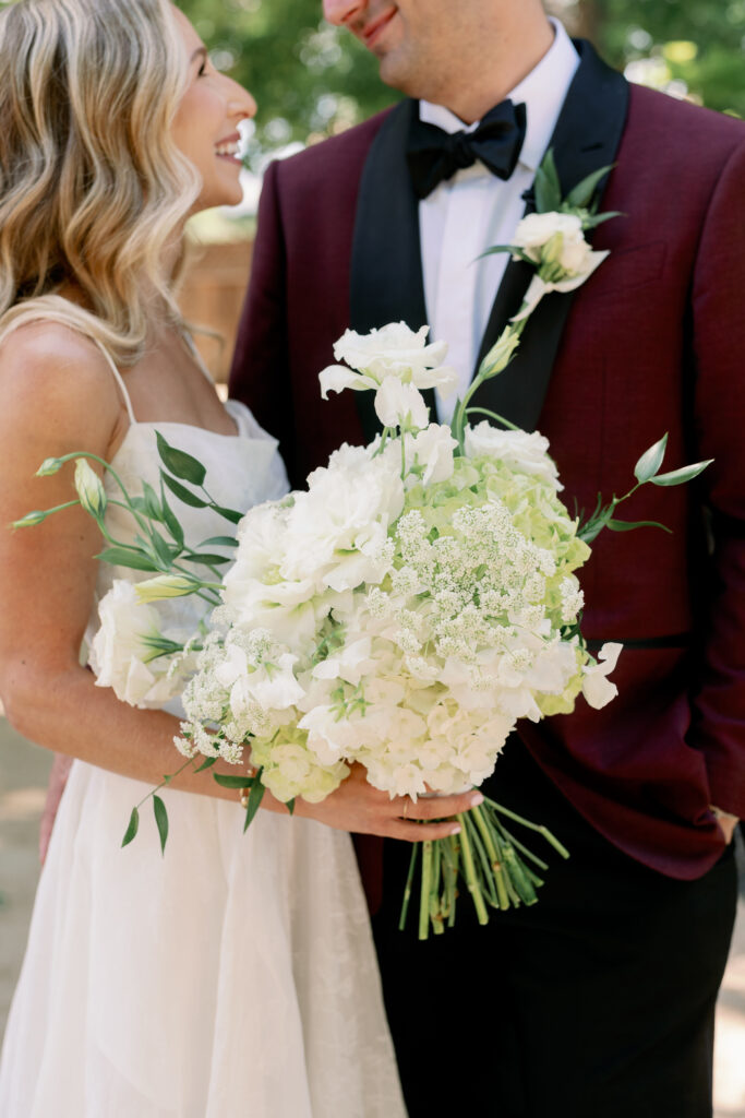 closeup photo of bridal bouquet with the bride and groom in the background