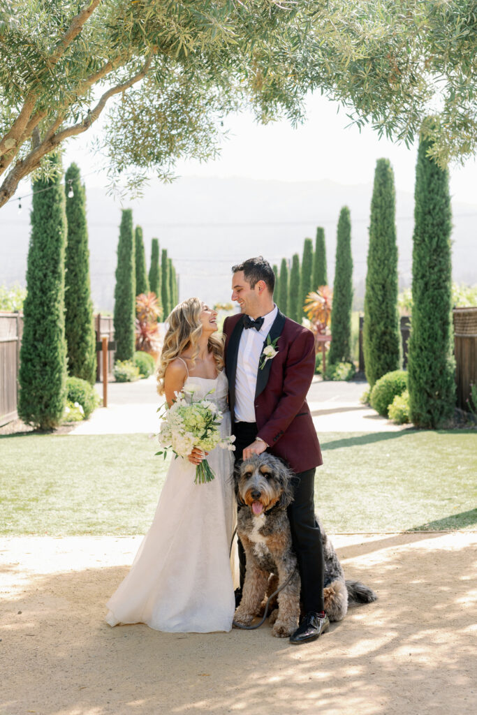 bride and groom posing for a picture with their dog